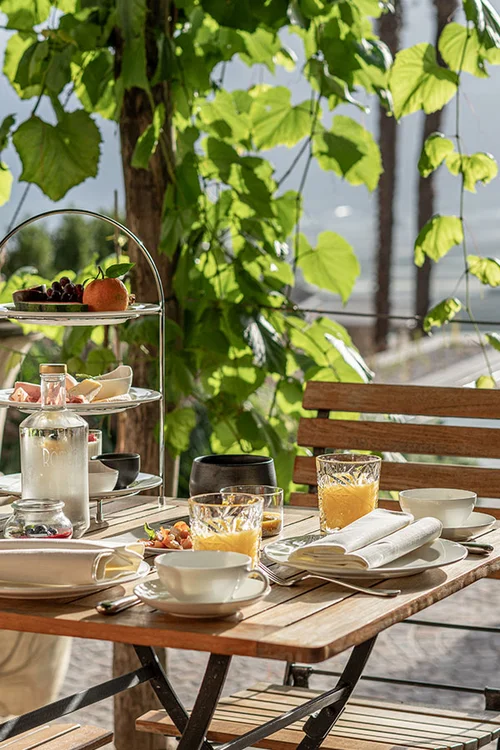 Frühstückstisch unter Weinlaub im Ansitz Romani – Hotel in Tramin, Südtirol
