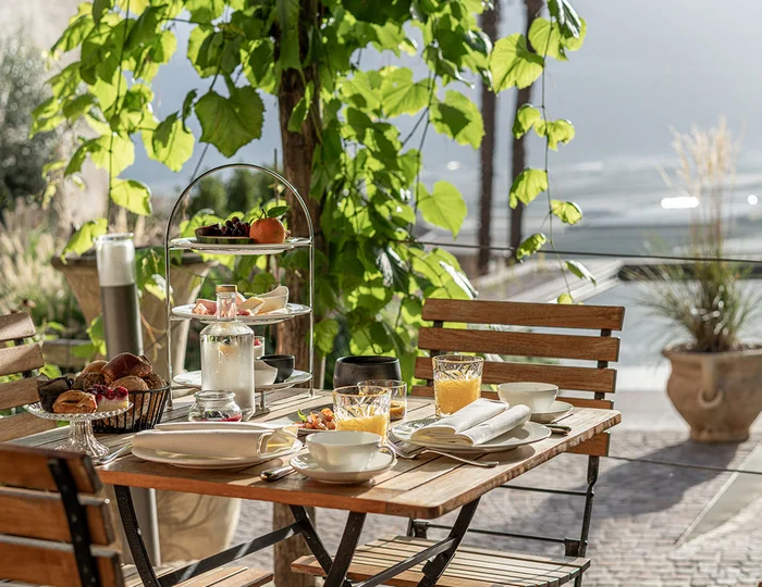 Frühstückstisch unter Weinlaub im Ansitz Romani – Hotel in Tramin, Südtirol