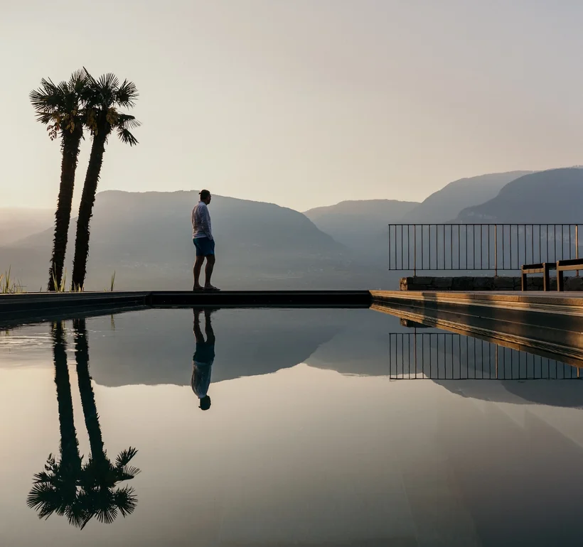 Bio-Pool des Ansitz Romani mit Palmen im Abendlicht – Hotel in Tramin, Südtirol