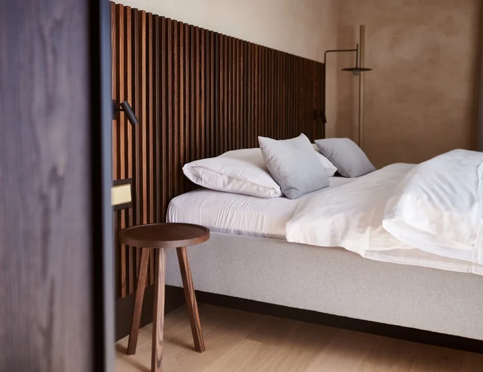 Doppelbett vor der Holzwand im Ansitz Romani – Hotel in Tramin, Südtirol