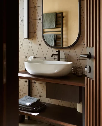 Badezimmer mit Rundspiegel im Ansitz Romani – Hotel in Tramin, Südtirol