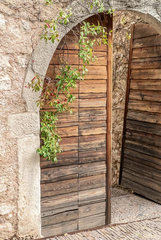 Steinbogen mit Holztor im Ansitz Romani – historisches Hotel in Tramin, Südtirol