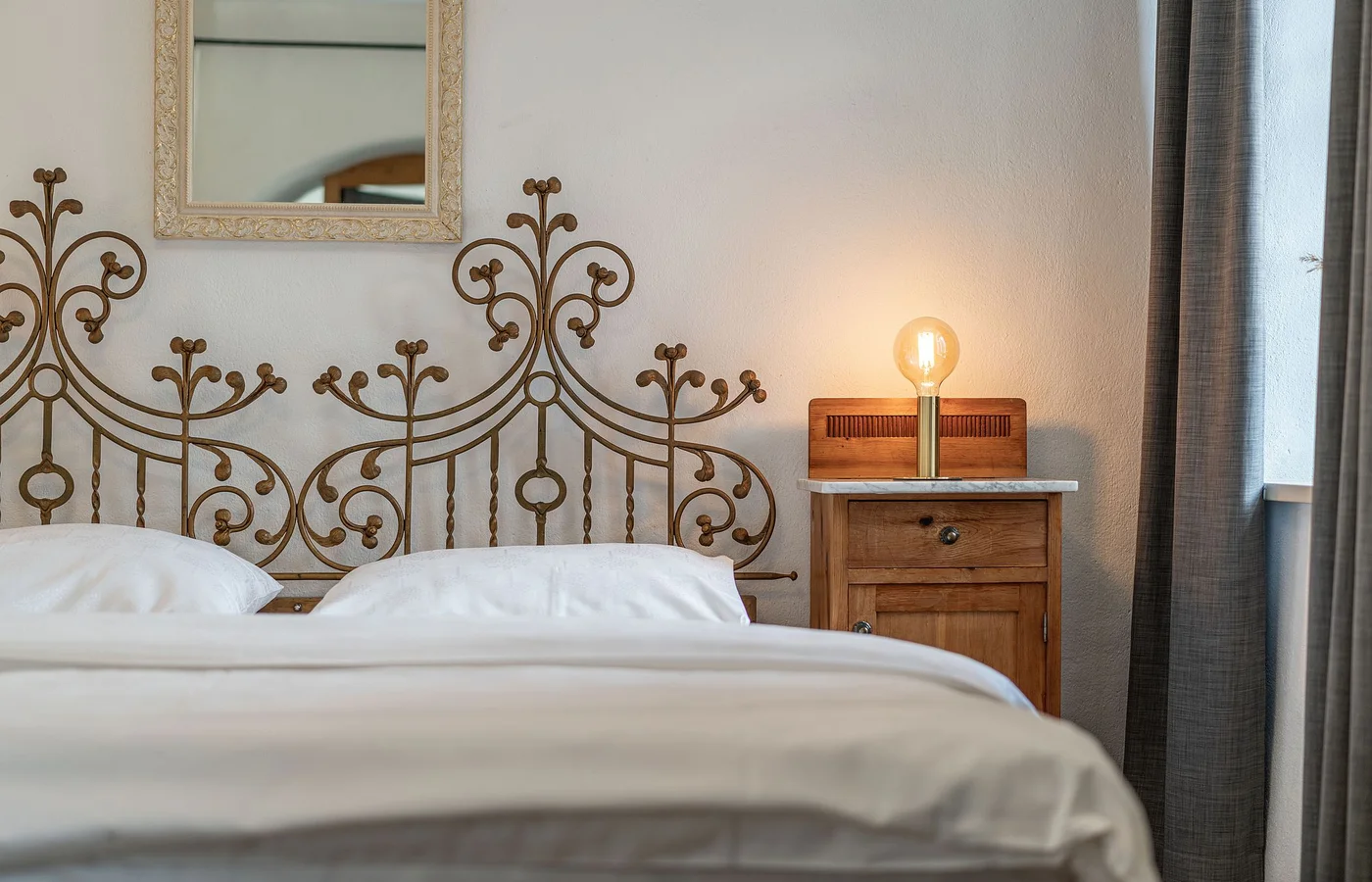 Zimmer II Fortuna: Bett mit verziertem Metallkopfteil – Zimmer im Ansitz Romani, Südtirol
