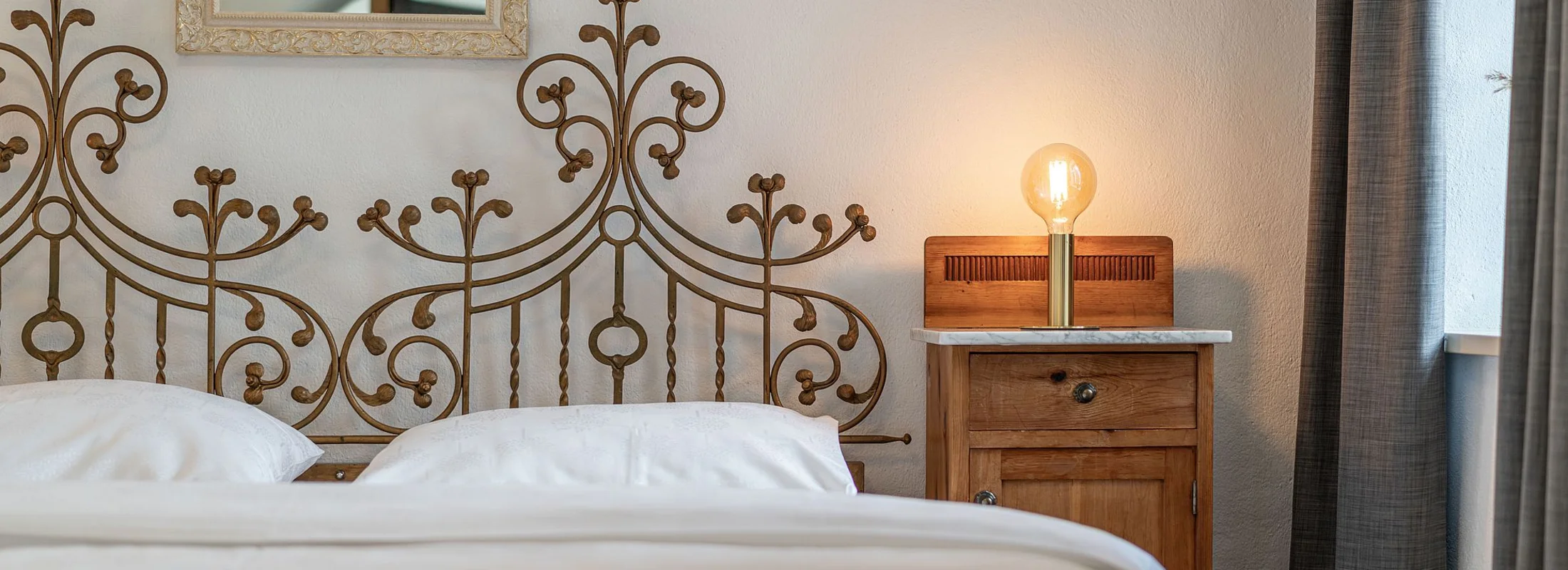 Zimmer II Fortuna: Bett mit verziertem Metallkopfteil – Zimmer im Ansitz Romani, Südtirol