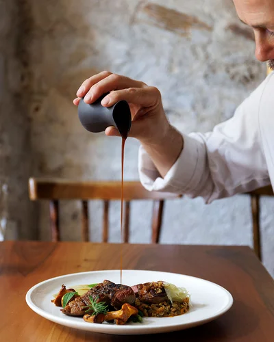 Haubenrestaurant Ansitz Romani: Anrichten eines Gerichts – regionale Küche in Tramin, Südtirol