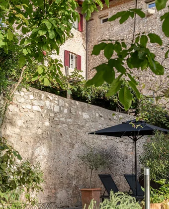Gartenmauer mit Sonnenschirm im Ansitz Romani – Hotel in Tramin, Südtirol